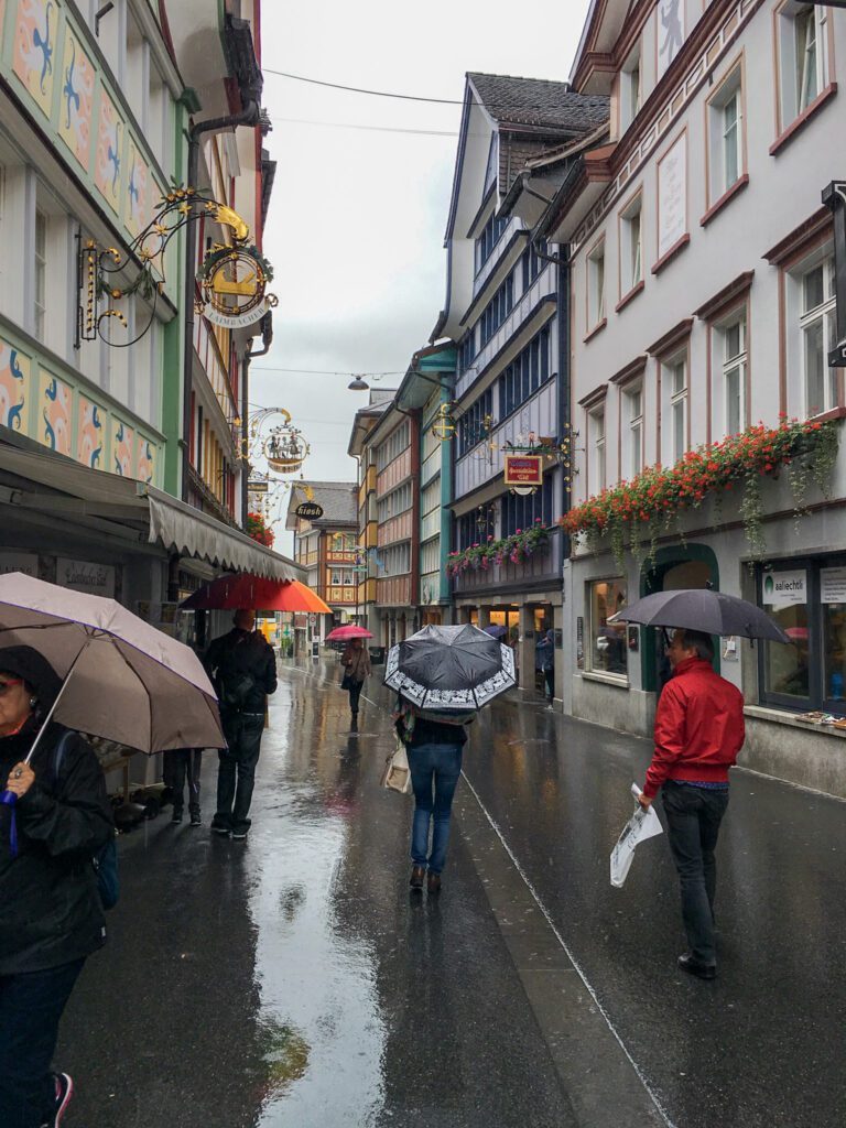 people walking in the rain with umbrellas in appenzell switzerland