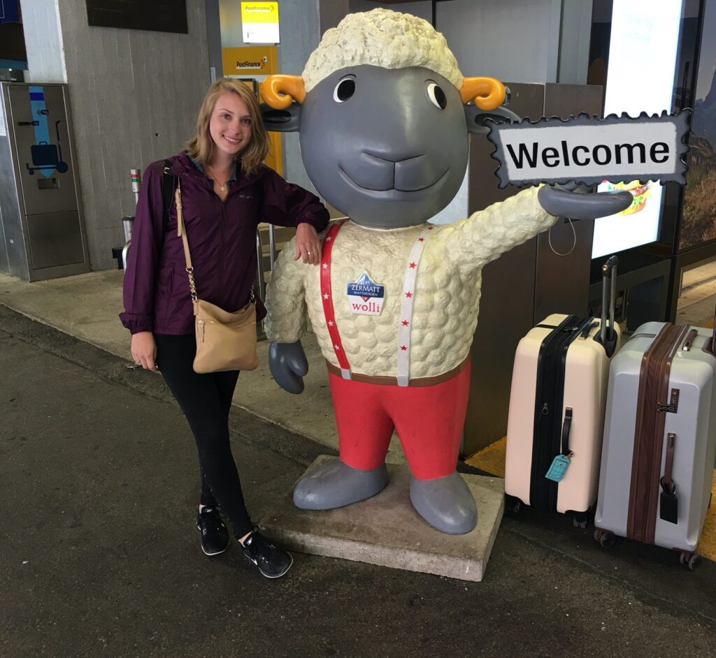 waiting by a welcome sign at the train station in Zermatt Switzerland